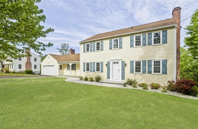 colonial inspired home with a chimney, a front lawn, asphalt driveway, and a garage