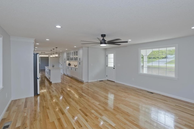 unfurnished living room featuring a chandelier, ceiling fan, light wood-type flooring, recessed lighting, and baseboards