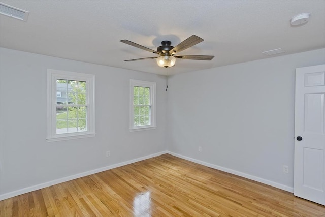 spare room with light wood finished floors, baseboards, a ceiling fan, and a smoke detector