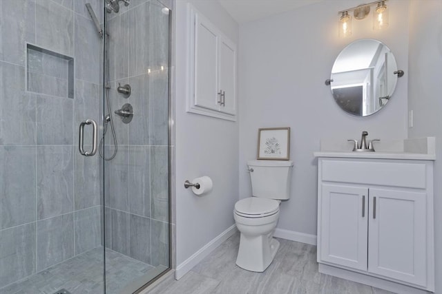 full bathroom featuring a stall shower, baseboards, vanity, and toilet