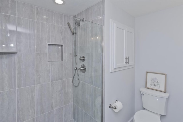 bathroom with a tile shower and toilet