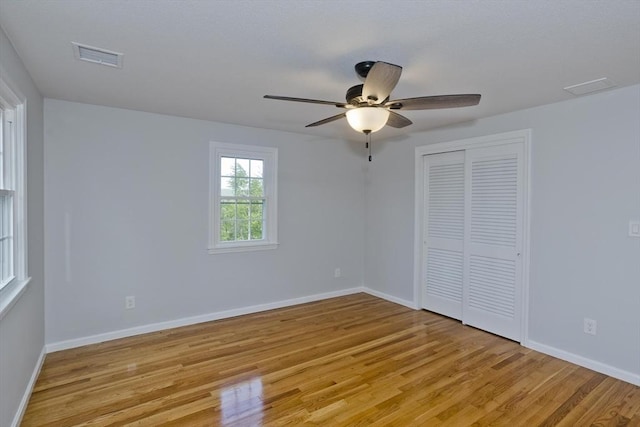 unfurnished bedroom with light wood-style floors, baseboards, a closet, and ceiling fan