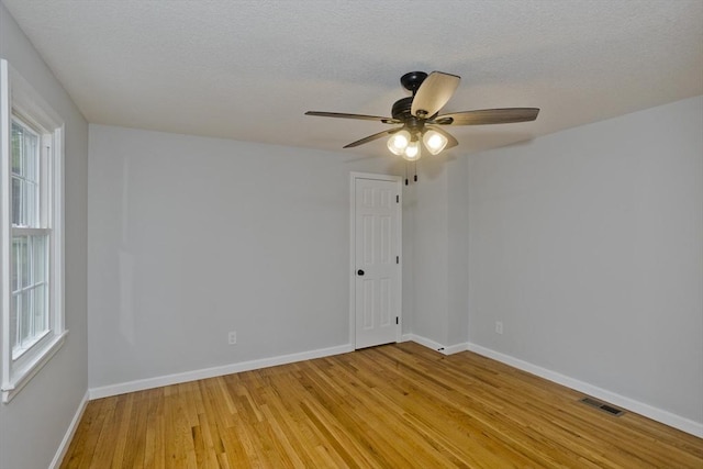 unfurnished room with light wood-style floors, a ceiling fan, baseboards, and a textured ceiling