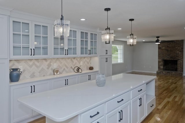 kitchen with light wood finished floors, a ceiling fan, white cabinetry, backsplash, and recessed lighting