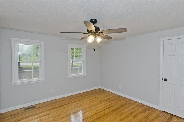 empty room featuring light wood finished floors, a ceiling fan, baseboards, and a textured ceiling