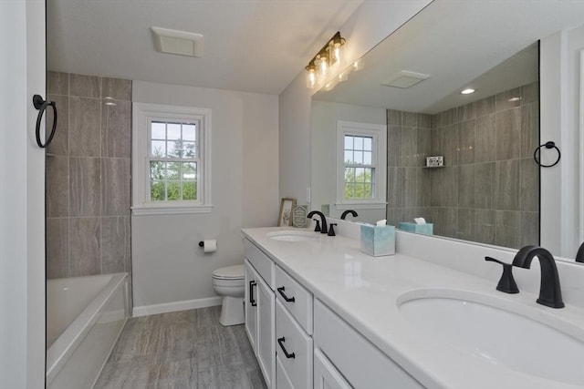 bathroom featuring healthy amount of natural light, baseboards, toilet, and double vanity