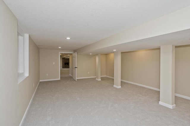 finished basement with light carpet, baseboards, recessed lighting, and a textured ceiling