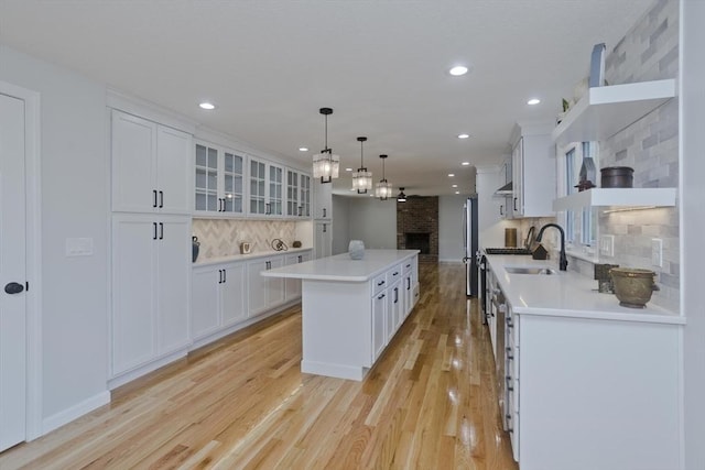 kitchen with a center island, white cabinetry, a brick fireplace, and recessed lighting