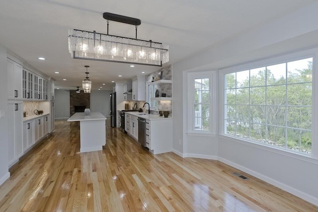 kitchen with freestanding refrigerator, light countertops, baseboards, a fireplace, and recessed lighting