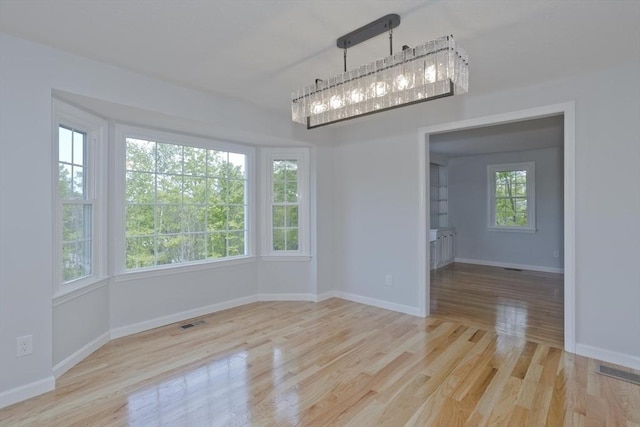 unfurnished dining area with wood finished floors, baseboards, and a chandelier