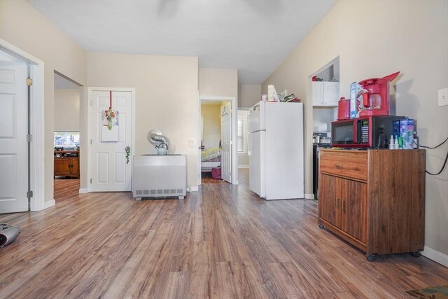 kitchen featuring baseboards, wood finished floors, and freestanding refrigerator