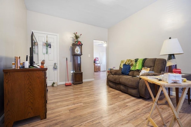 living room with baseboards, ceiling fan, and light wood-style floors