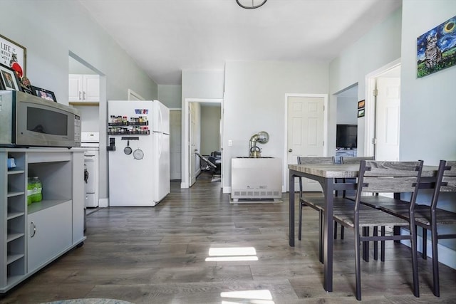 kitchen with dark wood-style floors, stainless steel microwave, freestanding refrigerator, light countertops, and white cabinetry