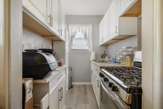 kitchen with light wood-type flooring, light countertops, white cabinets, and stainless steel gas stove