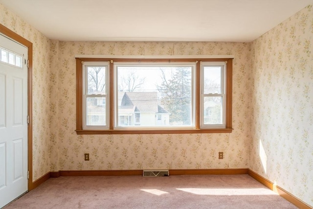 empty room with light colored carpet, visible vents, baseboards, and wallpapered walls