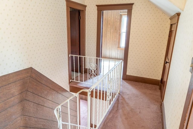 hall featuring carpet floors, lofted ceiling, baseboards, and wallpapered walls