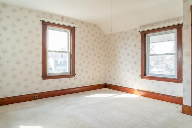 spare room with carpet floors, wallpapered walls, plenty of natural light, and lofted ceiling