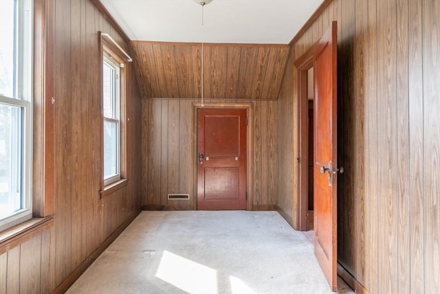 hallway featuring wood ceiling, a healthy amount of sunlight, wood walls, and light carpet