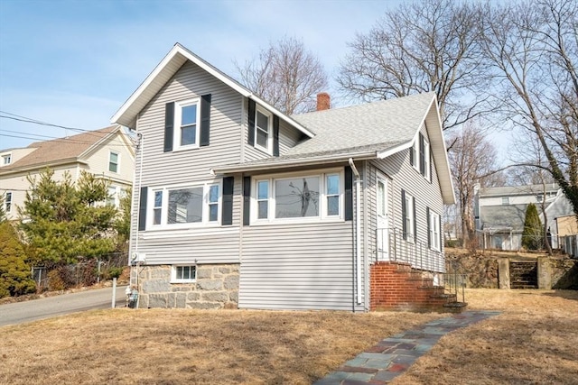 view of side of property featuring roof with shingles, a chimney, and a lawn