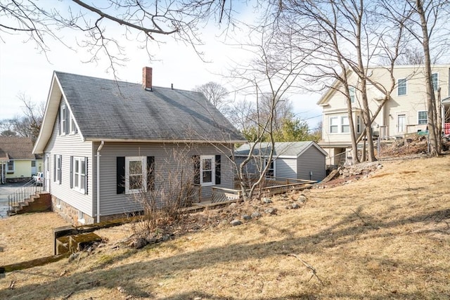 back of property featuring roof with shingles and a chimney