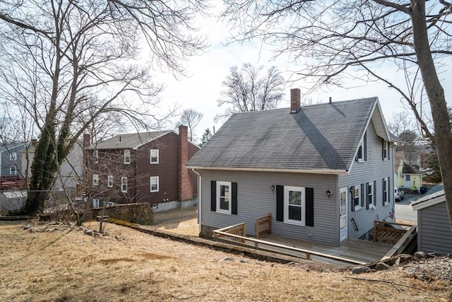 back of house with a shingled roof, a chimney, fence, and a wooden deck