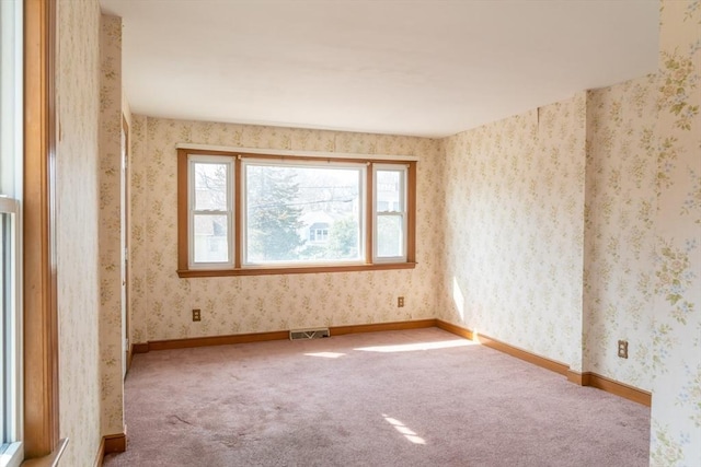 carpeted spare room with wallpapered walls, baseboards, and visible vents