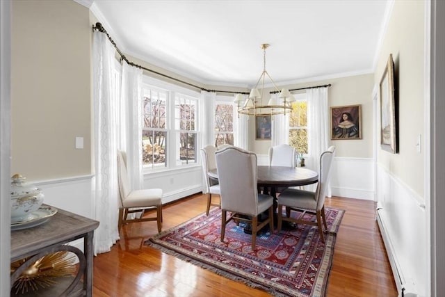 11 Paige St, Hingham, MA 02043 - dining room featuring a chandelier, ornamental molding, wood finished floors, a wainscoted wall, and baseboard heating