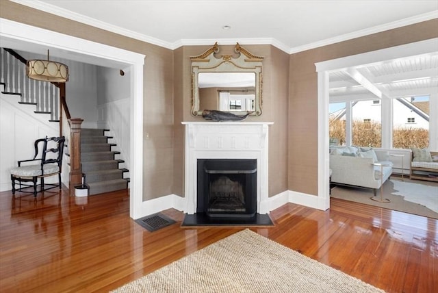11 Paige St, Hingham, MA 02043 - living area with wood finished floors, baseboards, stairway, a fireplace with raised hearth, and crown molding