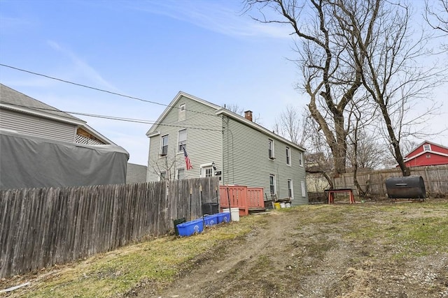 view of property exterior with heating fuel, a fenced backyard, and a chimney