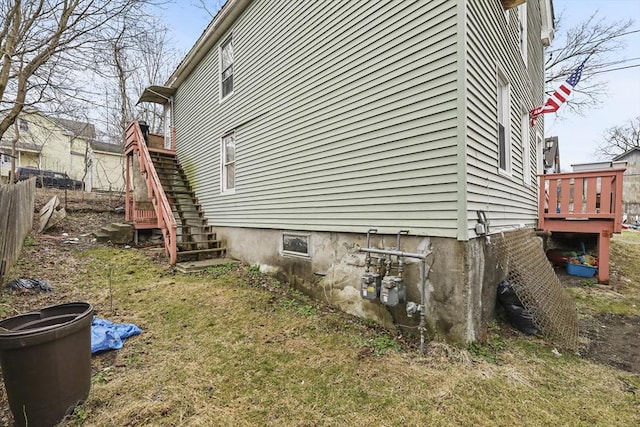 view of side of property with a lawn, fence, a deck, and stairs