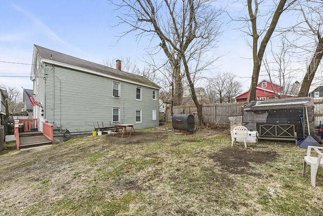 rear view of house featuring fence and heating fuel