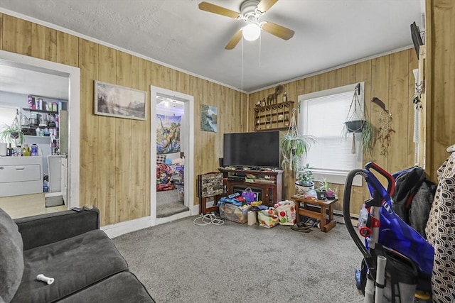 carpeted living area with crown molding, wood walls, and a ceiling fan
