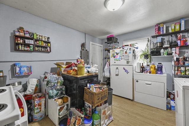kitchen featuring freestanding refrigerator, washer and clothes dryer, and light wood-style floors