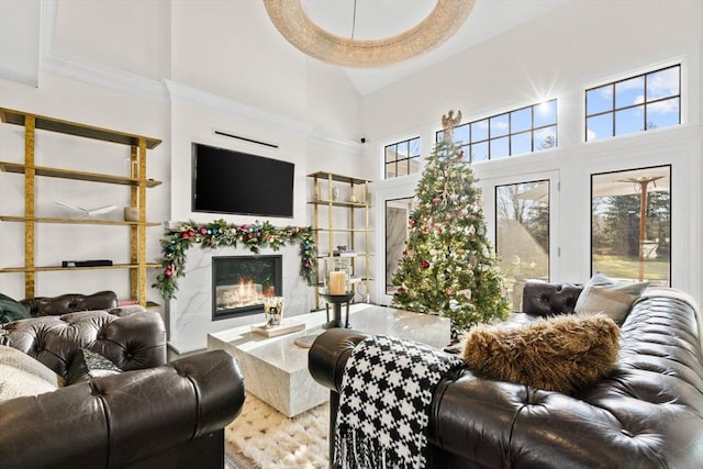 living room with a towering ceiling, a high end fireplace, and ornamental molding