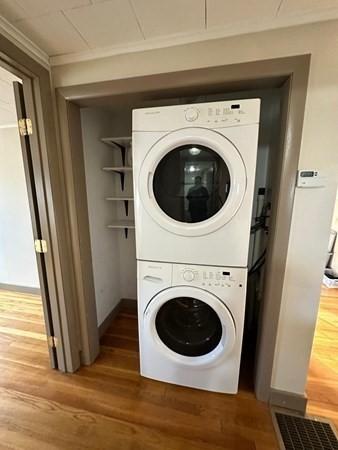 91 W Main St, West Brookfield, MA 01585 - laundry room featuring wood finished floors, stacked washing maching and dryer, baseboards, ornamental molding, and laundry area