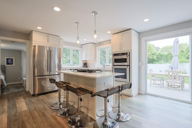 5 Birch Hill Rd, Dennis, MA 02639 - kitchen with stainless steel appliances, light wood finished floors, white cabinets, a breakfast bar, and recessed lighting