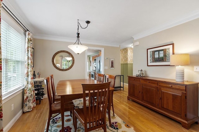 dining room with light wood-style flooring, ornamental molding, and baseboards
