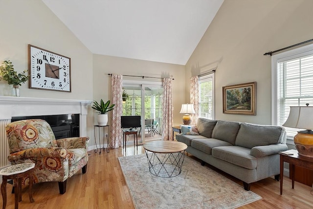 living room with light wood-style flooring, high vaulted ceiling, and baseboards