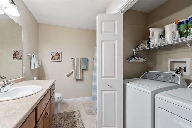 washroom with separate washer and dryer, light tile patterned floors, and baseboards