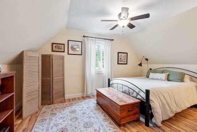 bedroom with lofted ceiling, light wood-style flooring, ceiling fan, and baseboards