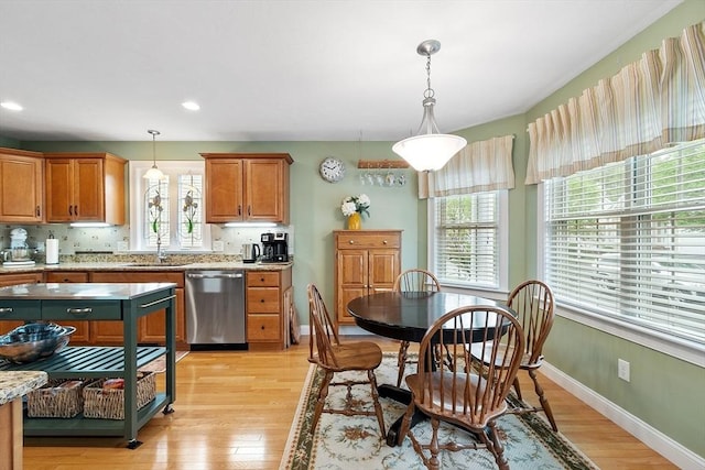 kitchen featuring stainless steel dishwasher, plenty of natural light, a sink, light wood-type flooring, and recessed lighting