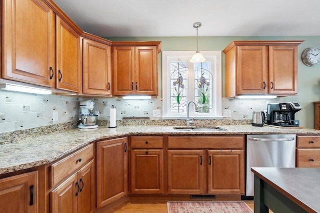 kitchen with a sink, dishwasher, decorative light fixtures, and brown cabinets