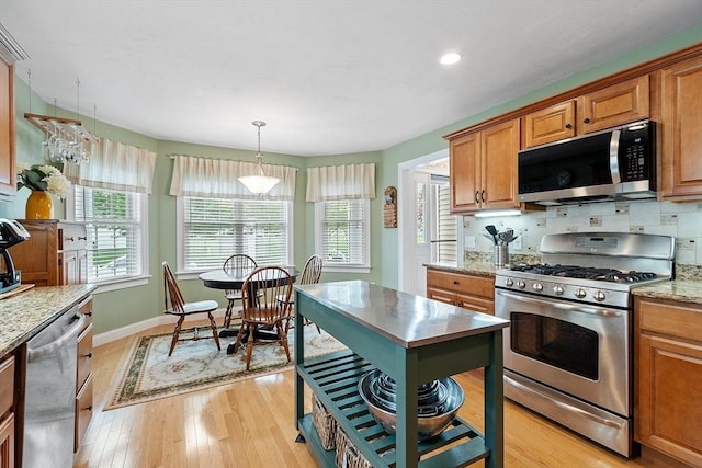kitchen featuring appliances with stainless steel finishes, light wood-type flooring, brown cabinets, recessed lighting, and baseboards