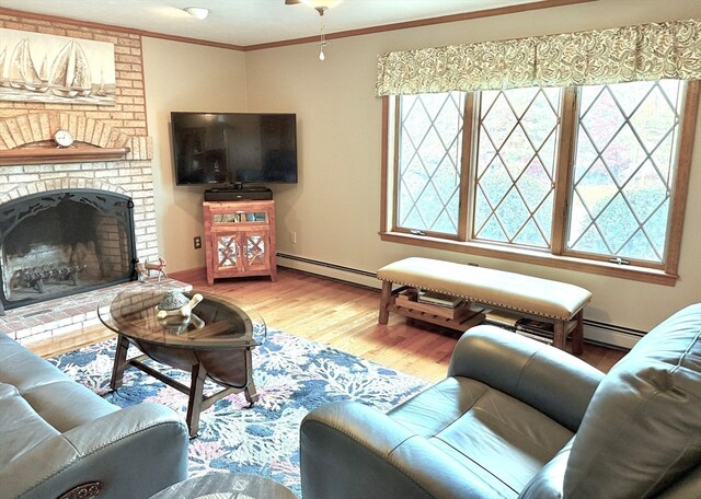 living room featuring a wealth of natural light, wood-type flooring, a baseboard heating unit, and ornamental molding