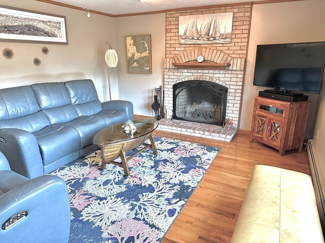 living room with hardwood / wood-style floors, ornamental molding, a baseboard radiator, and a brick fireplace