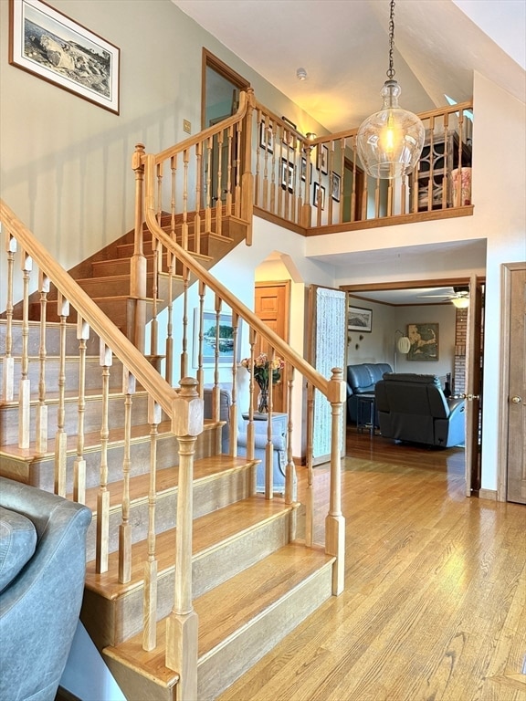 stairs with hardwood / wood-style floors and a towering ceiling