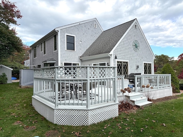 rear view of property featuring a deck, a yard, and a storage shed