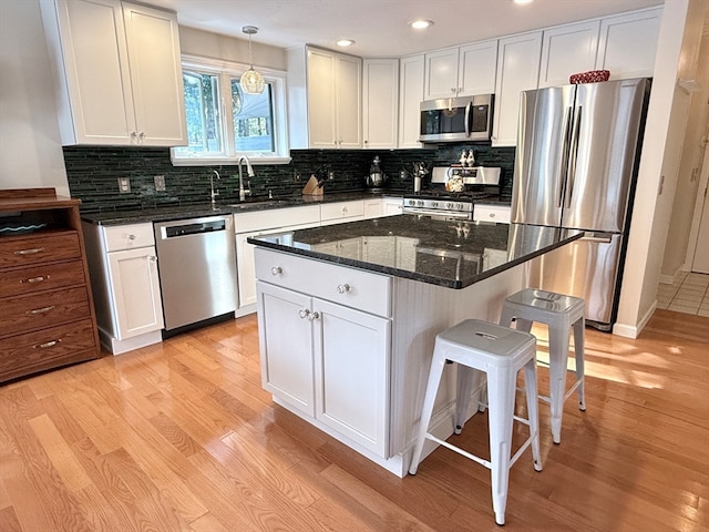 kitchen featuring pendant lighting, stainless steel appliances, sink, and white cabinets