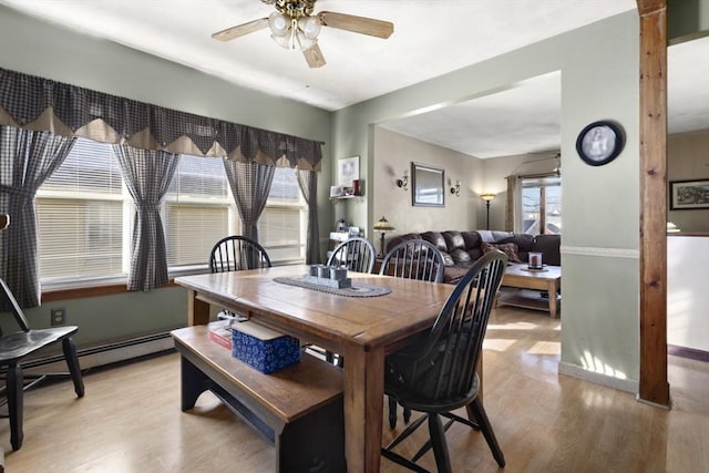 dining room with ceiling fan, a baseboard radiator, light hardwood / wood-style flooring, and a wealth of natural light