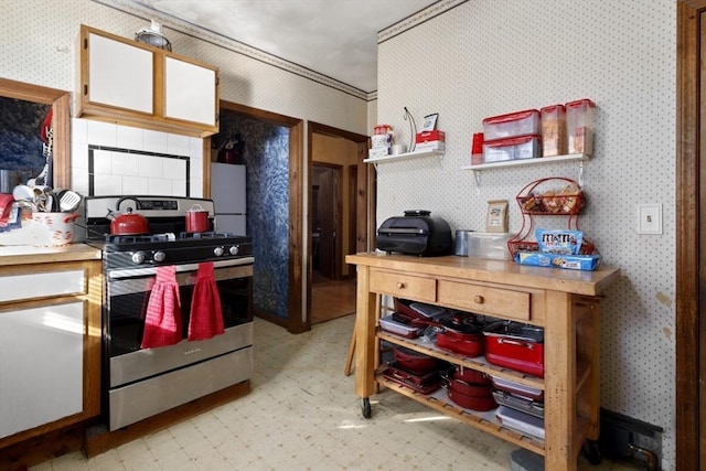 kitchen with stainless steel gas stove, ornamental molding, and white fridge